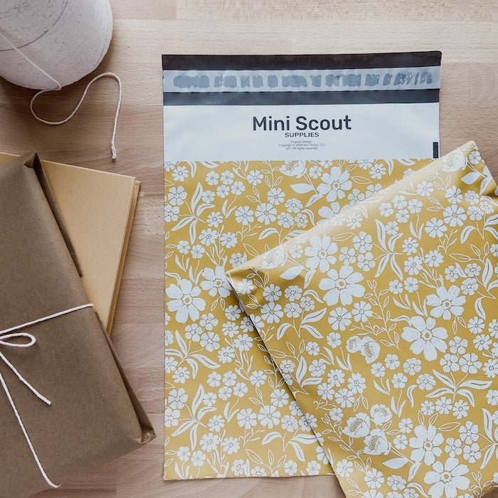 yellow polymailer laid flat over a wooden desk beside a brown package and twine shown half