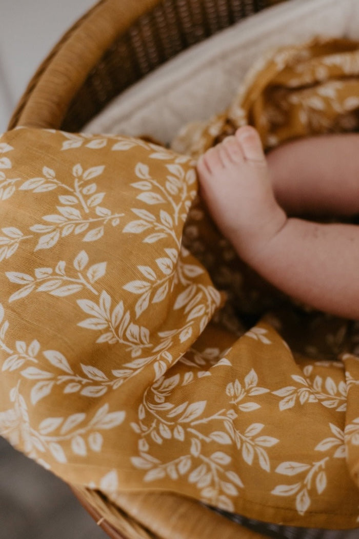 yellow a close up of the mustard swaddle baby boy blankets with a teeny tiny baby feet on top of it