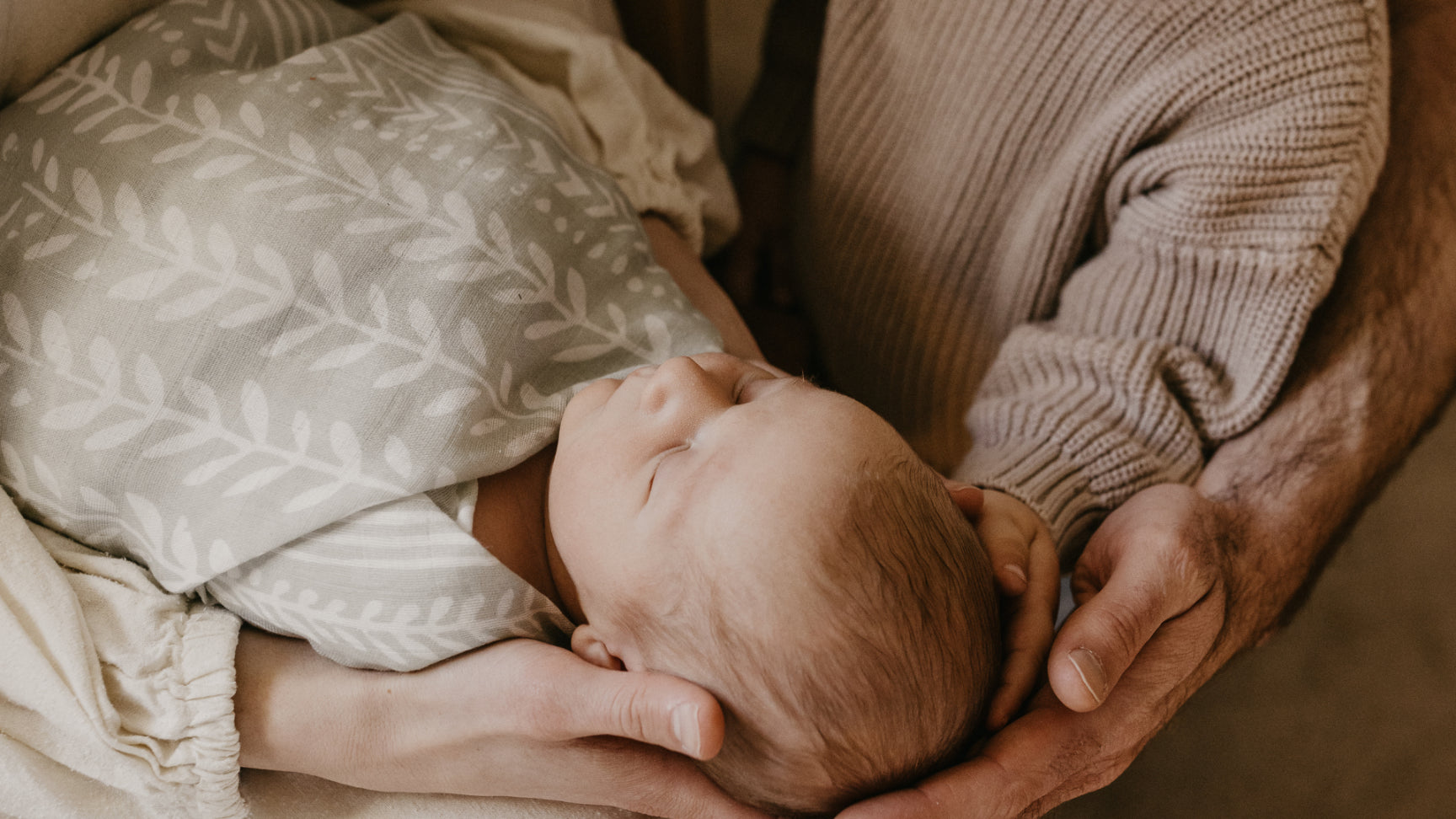 newborn photo with baby swaddled in a green mini wander blanket with his family
