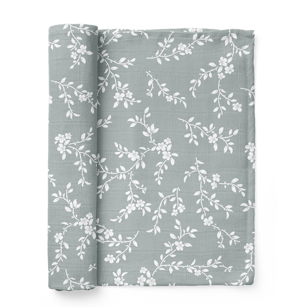 folded bloom floral muslin swaddle showing the little white leaves and flowers in a nice blue background