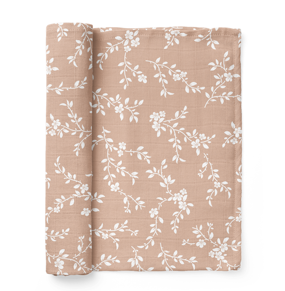 bloom peach swaddle blanket rolled on the side showing the white petals in the peach background