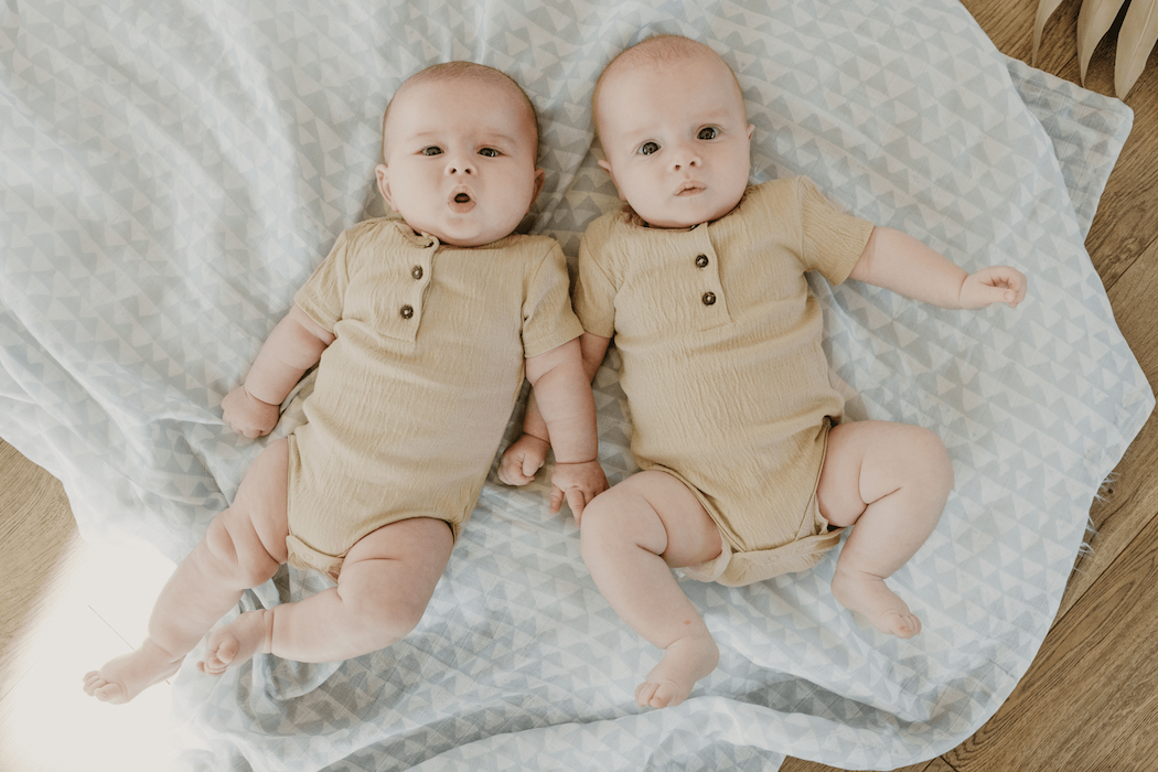cute and cuddly twin babies lying on top of the blue swaddle blanket