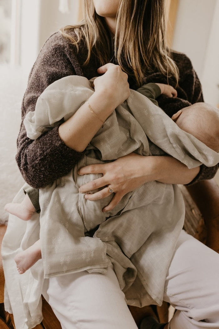 mom breastfeeding her baby using the christmas swaddle as a cover