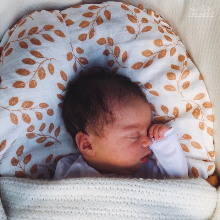 sweet baby boy sleeping with the cotton infant summer swaddle amber leaves print used as a pillow cover