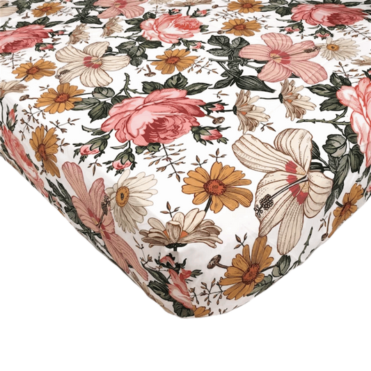 a closeup look of the vintage floral crib sheet showcasing the beautiful daisies, hibiscus and roses in a white background the perfect cotton crib sheets