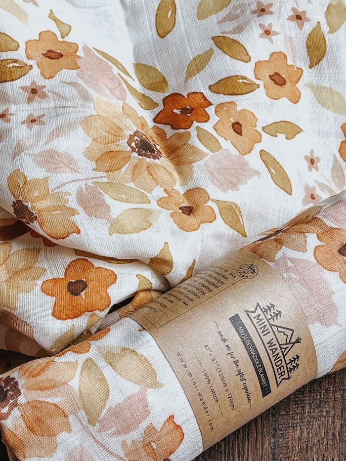 Two sunflower baby blanket rolled and opened showing the Mini Wander logo in a kraft paper which is a perpect gift for autumn babies