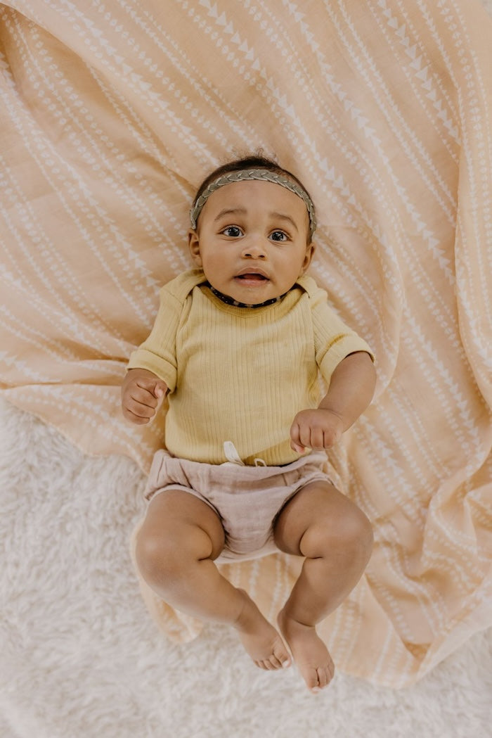 Little baby girl looking pleasantly surprised as she lays on her tribal receiving blanket as a photo op background