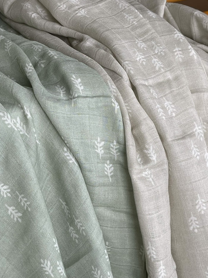 unwrapped and unrolled baby muslin blanket hanging freely and loosely showing the entire print and design of the tiny trees in triangular patterns that would make a perfect baby boy lovey or babys first christmas gifts