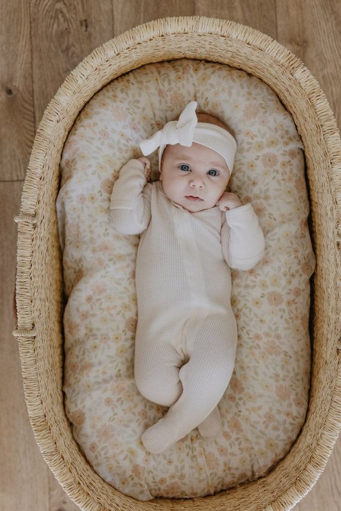 baby girl in a baby bassinet covered with meadow cream muslin swaddles made with natural cotton
