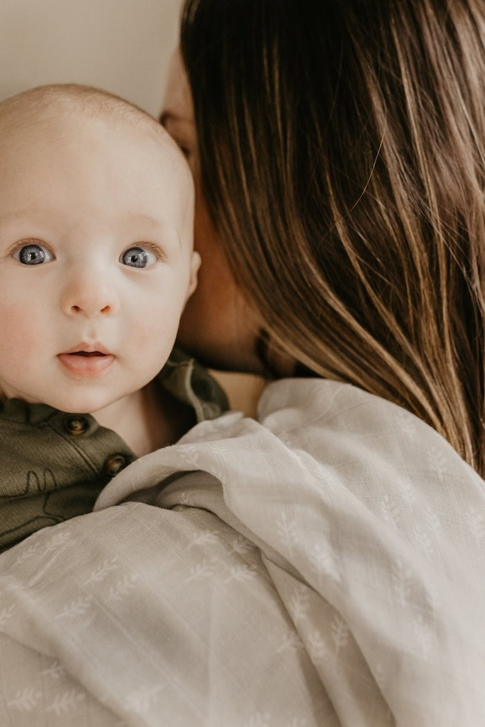 baby looking at the camera carried by mom with the christmas swaddle forest gray wolf in her shoulders