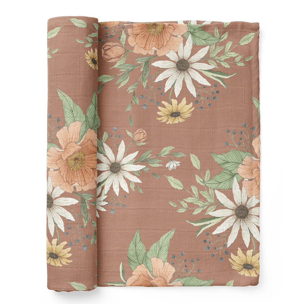 a photo of the folded spring blossom clay muslin baby swaddles showcasing the sunflowers, peonies and delicate buds