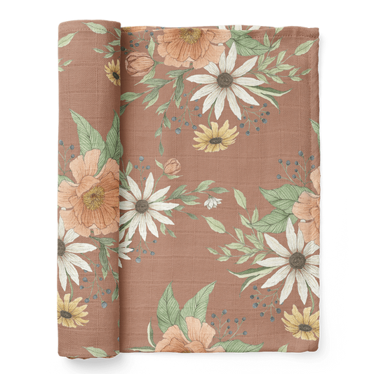 a photo of the folded spring blossom clay muslin baby swaddles showcasing the sunflowers, peonies and delicate buds