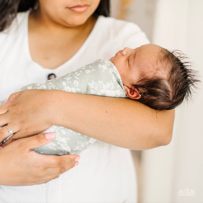 mom and baby photo with mom holding her baby wrapped in a green vintage bouquet swaddle blanket