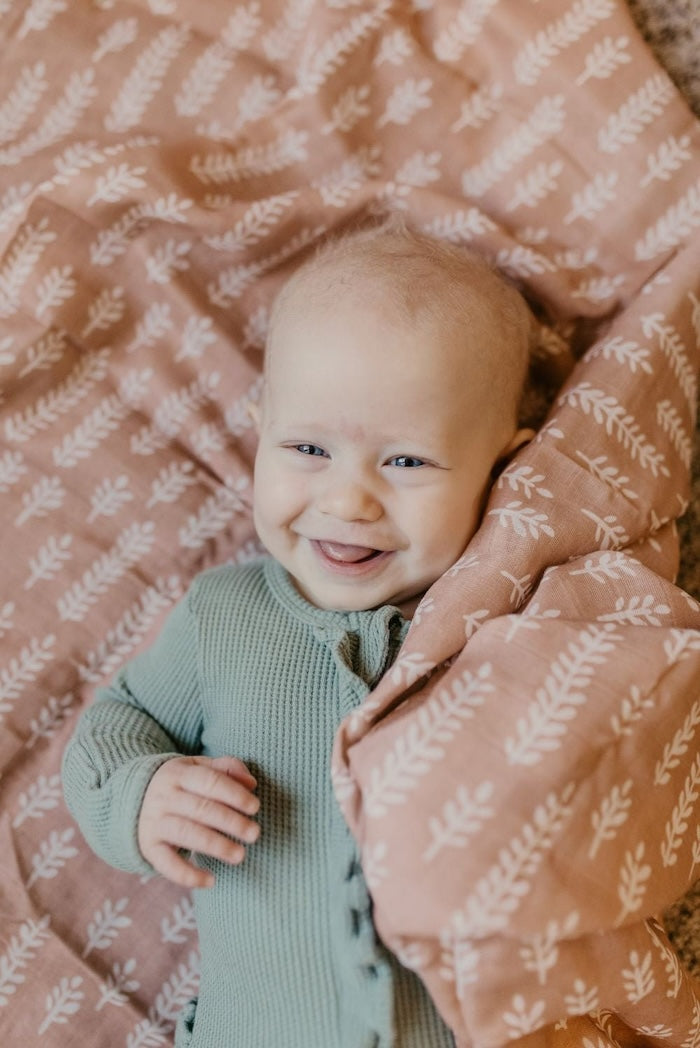 photo of a smiling baby tongue out lying on top of the muslin blankets