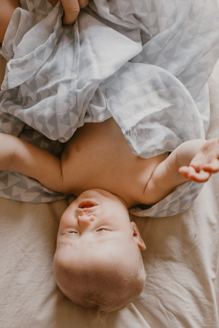 baby boy wrapped cozily in a blue swaddle blanket in a triangle swaddle design