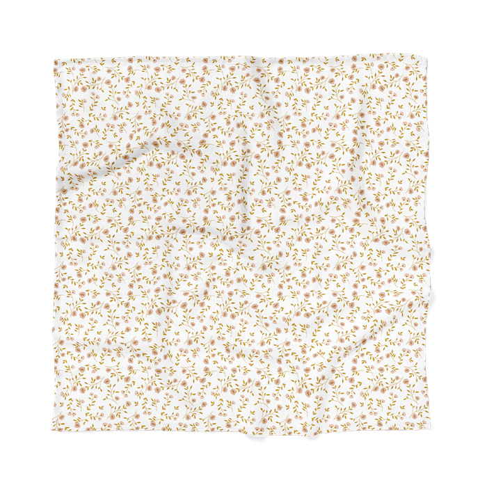 The Mini Wander wildflower white floral baby blanket laid flat showing the wildflowers pink pattern and tiny leaves