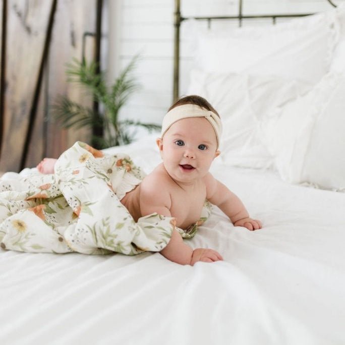 chubby baby tummy time in her cozy bed using the spring blossom peony swaddle as a blanket