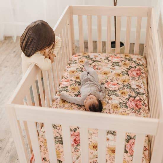 siblings precious moments with the little baby lying in the crib covered with the favorite nursery decor which is the pink crib sheets while big sister looking down at her