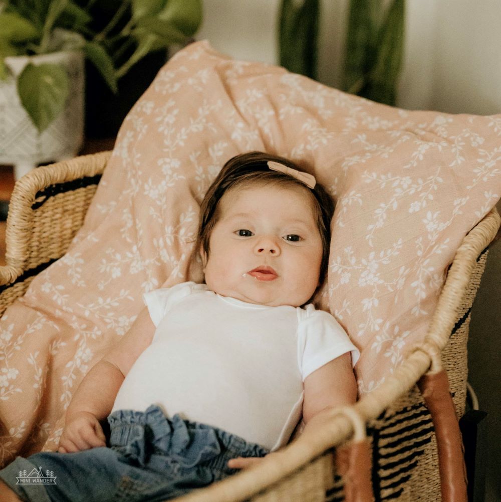 a sweet girl lounging on her peach summer blanket while looking blankly at the camera