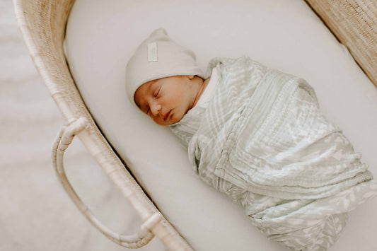 baby boy swaddled and sleeping in bassinet