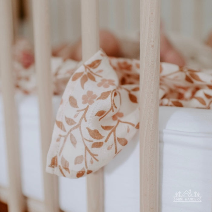 magnolia tree brown blanket hanging on the side of a wooden crib 