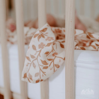 magnolia tree brown blanket hanging on the side of a wooden crib 