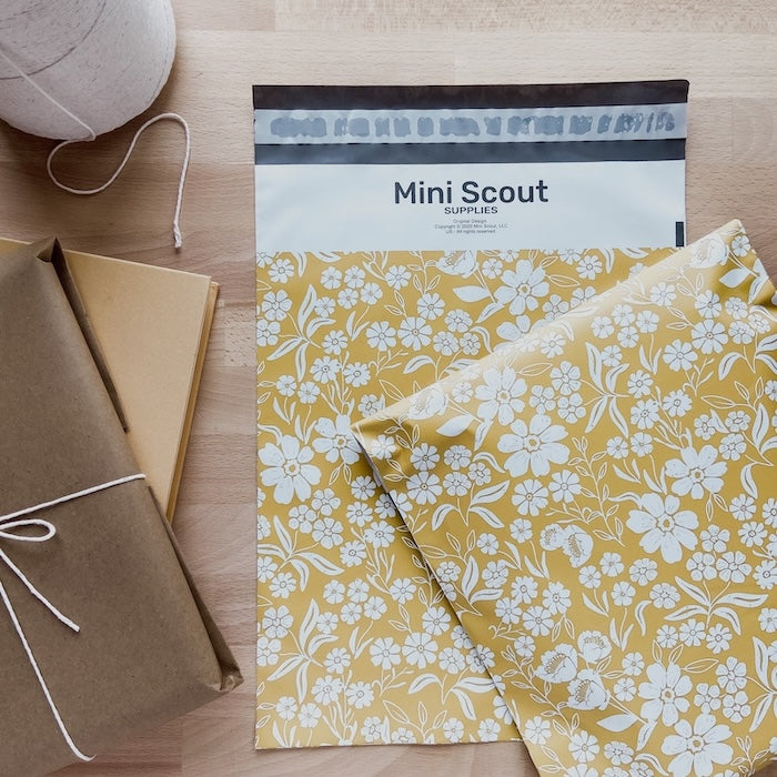 flatlay photo of the yellow floral polymailer beside a brown package and twine