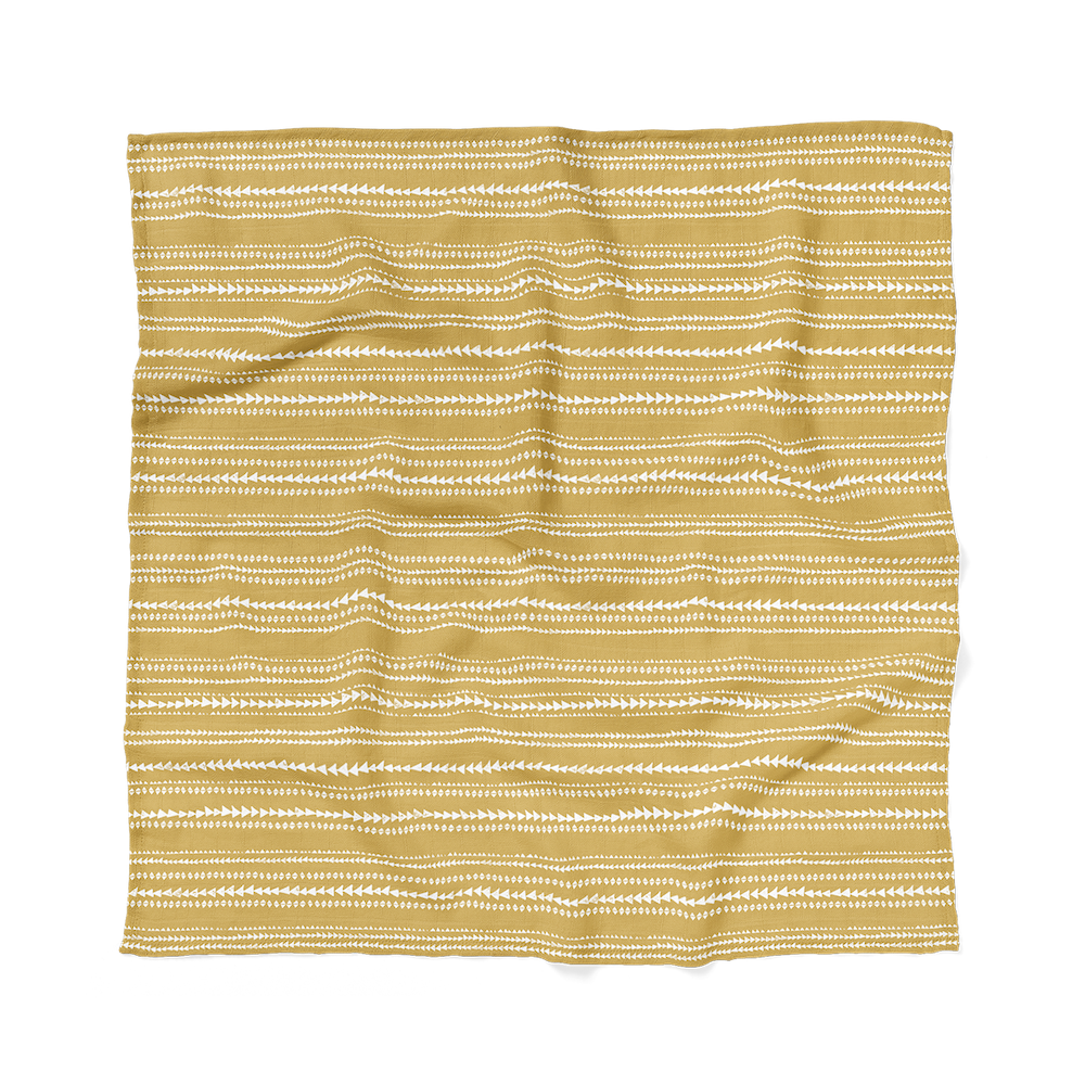 an image of a newborn blanket, a terrain muslin swaddle wrap laid flatly showing the dusty yellow aztec pattern that will match perfectly to any boho baby boy clothes