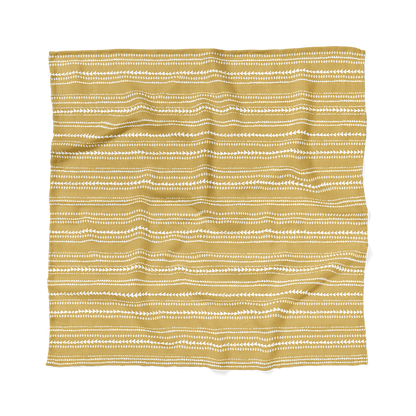 an image of a newborn blanket, a terrain muslin swaddle wrap laid flatly showing the dusty yellow aztec pattern that will match perfectly to any boho baby boy clothes