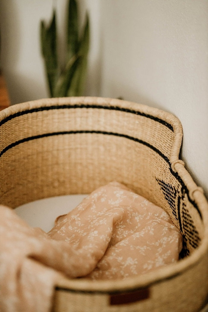 a peach summer blanket thrown inside the baby bassinet creating that nice flowy texture