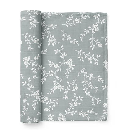 folded bloom floral muslin swaddle showing the little white leaves and flowers in a nice blue background