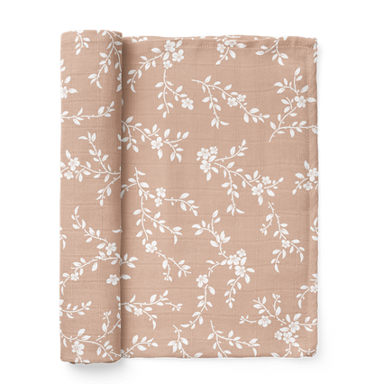 bloom peach swaddle blanket rolled on the side showing the white petals in the peach background