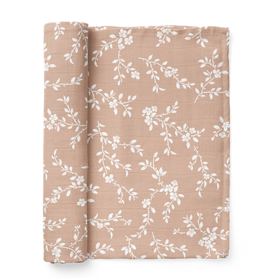 bloom peach swaddle blanket rolled on the side showing the white petals in the peach background