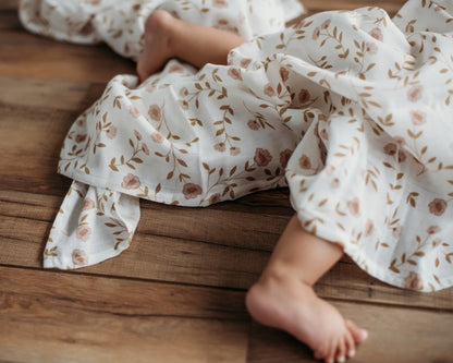baby's teeny tiny feet slightly covered with the wildflower white floral baby blanket