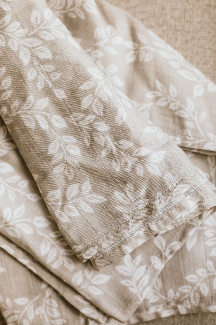 a close up photo of the muslin swaddle blankets boy highlighting the leafy sprig design