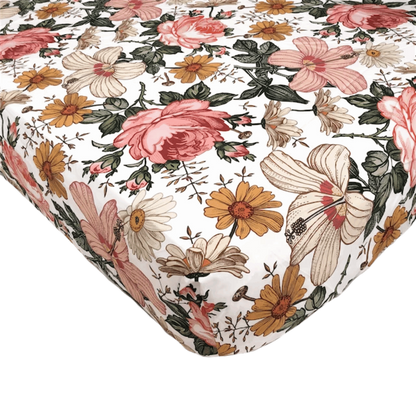 a closeup look of the vintage floral crib sheet showcasing the beautiful daisies, hibiscus and roses in a white background the perfect cotton crib sheets