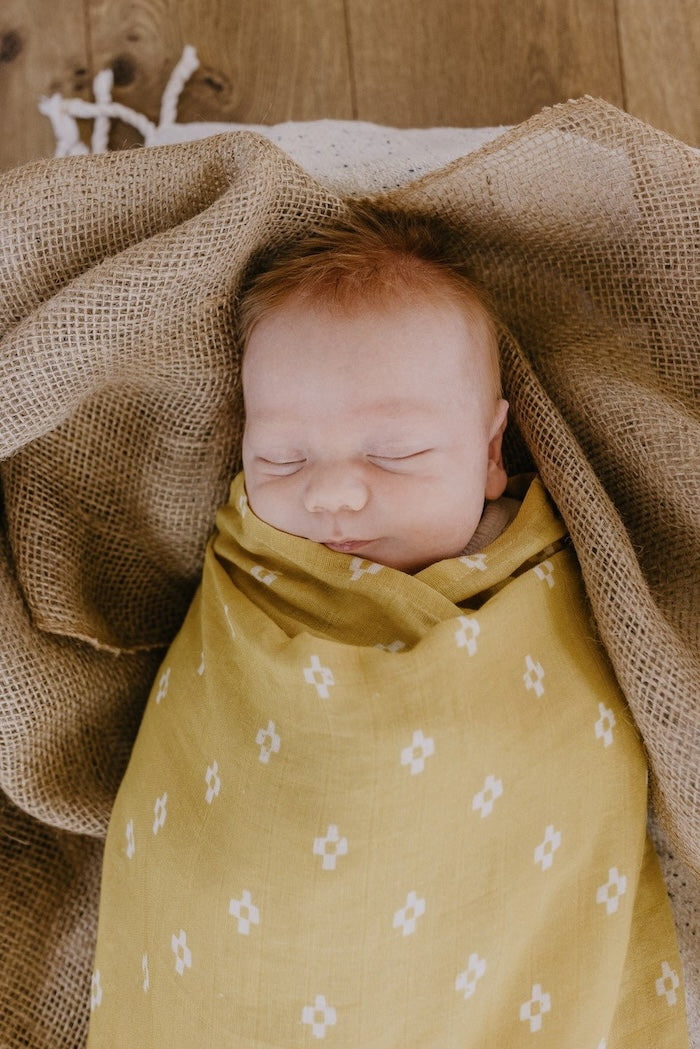 sleeping baby swaddled in a yellow baby blanket