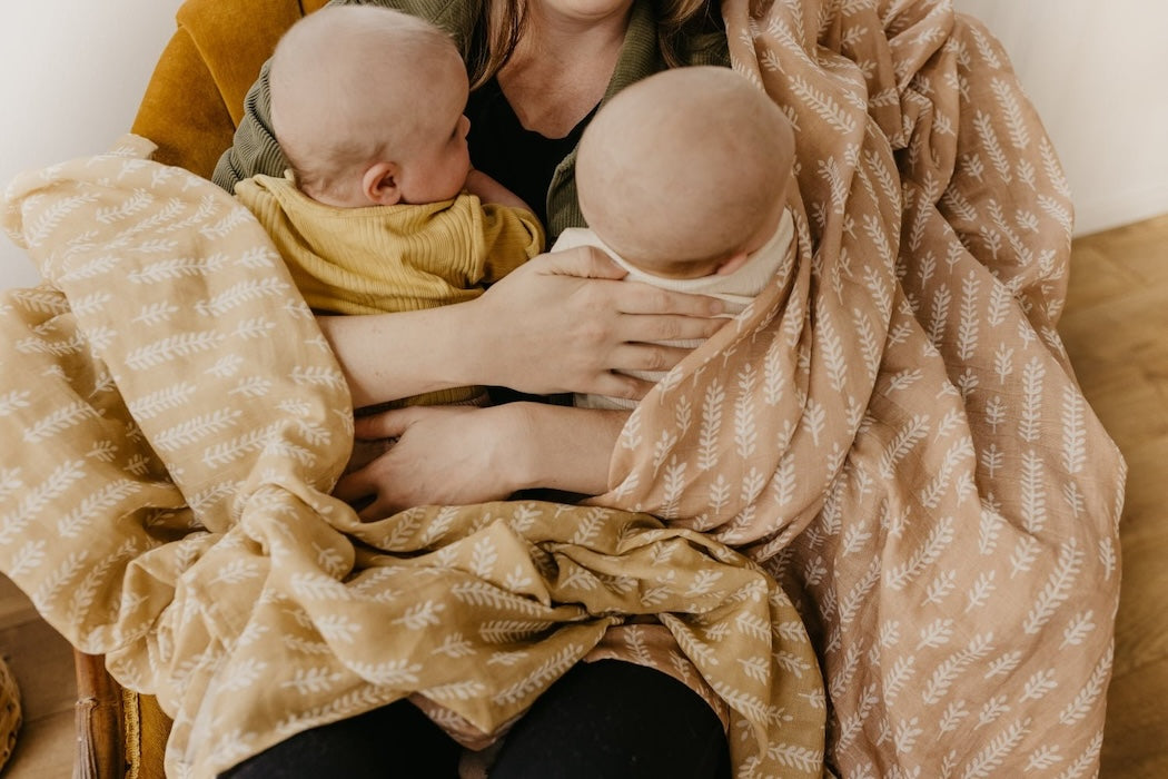 a sweet photo of mom cuddling her twin babies wrapped in our cream baby blanket in gender neutral baby blanket colors