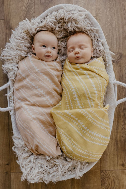 two cute and adorable babies lying on a baby basket wrapped in ur tribal receiving blanket in Apricot and Yellow colors