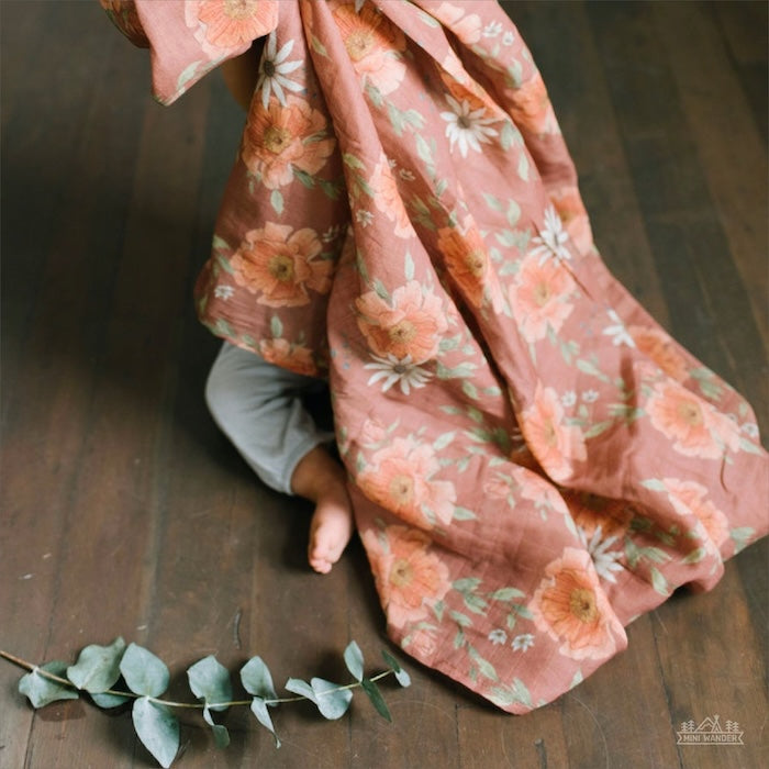 cute boho nursery floral baby swaddle blanket held by the baby covering the body used for playtime and peekaboo