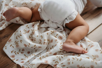 a crawling baby showing half of her body wearing cute baby clothes and the rest of her feet with her toes touching the wildflower white floral baby blanket