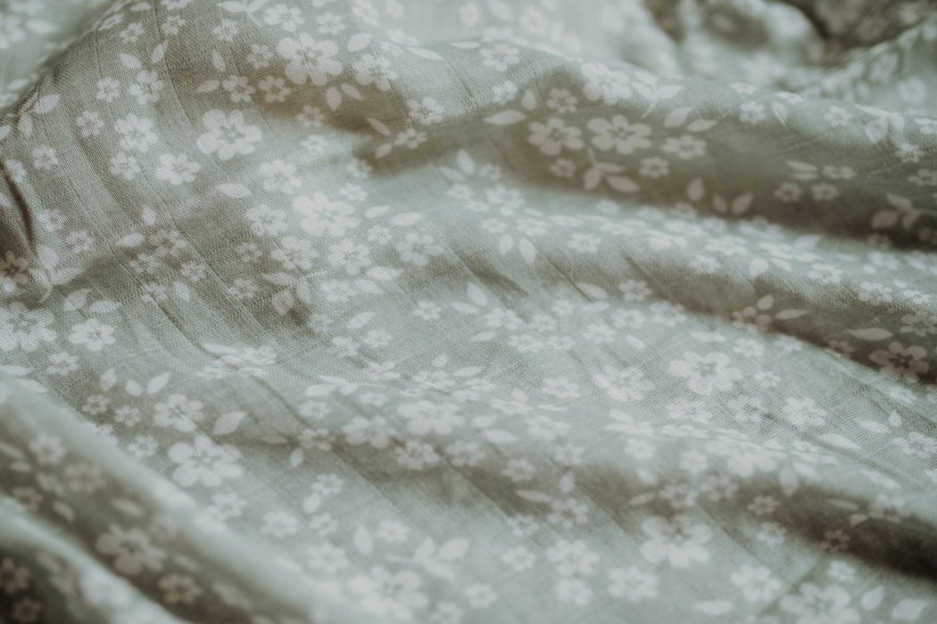 A close-up of Mini Wander sage green with white floral design laid loosely.