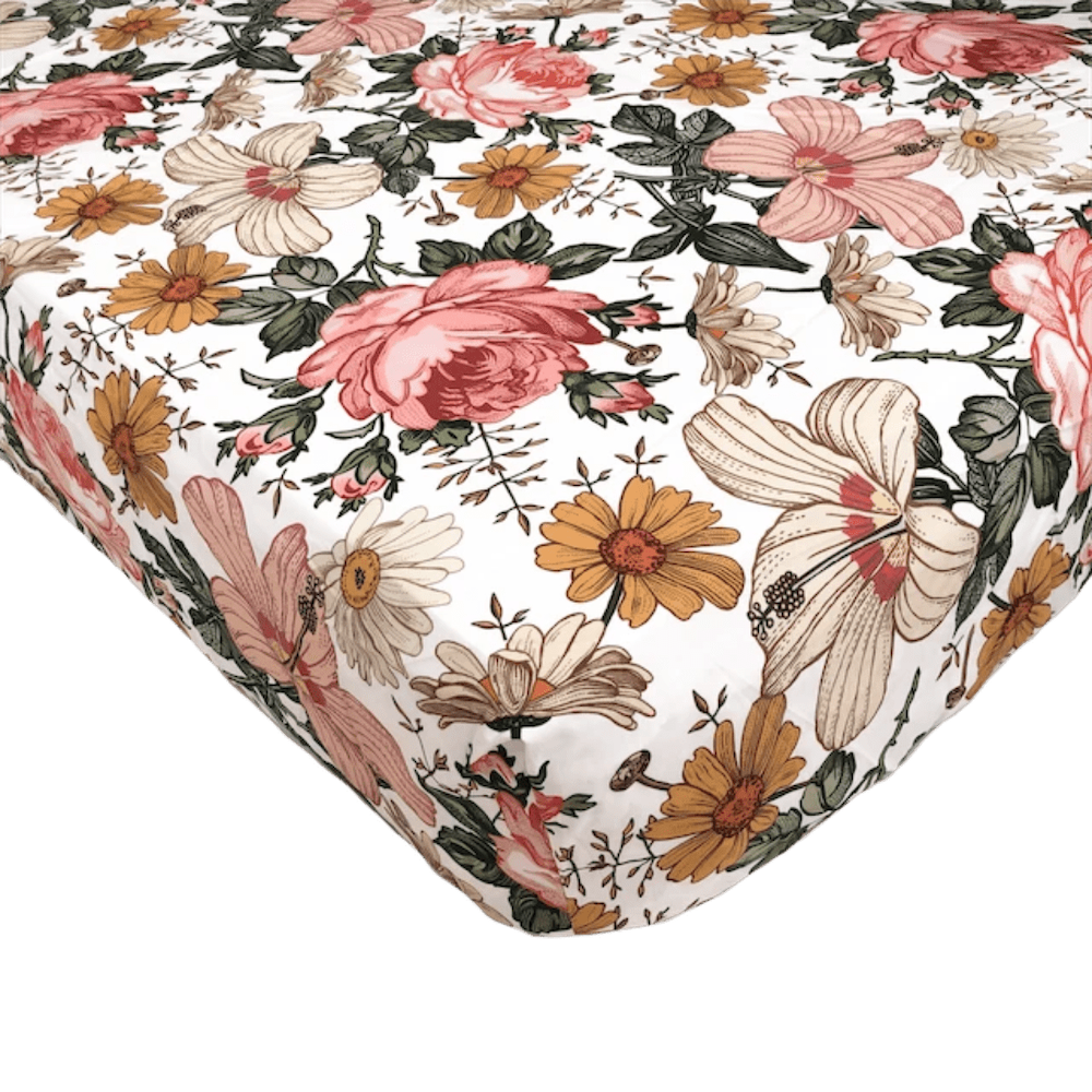 a close up look of the vintage floral crib sheet with the bold and stunning combination of hibiscus blooms, roses and daisies in a white background