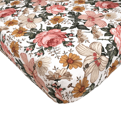 a close up look of the vintage floral crib sheet with the bold and stunning combination of hibiscus blooms, roses and daisies in a white background