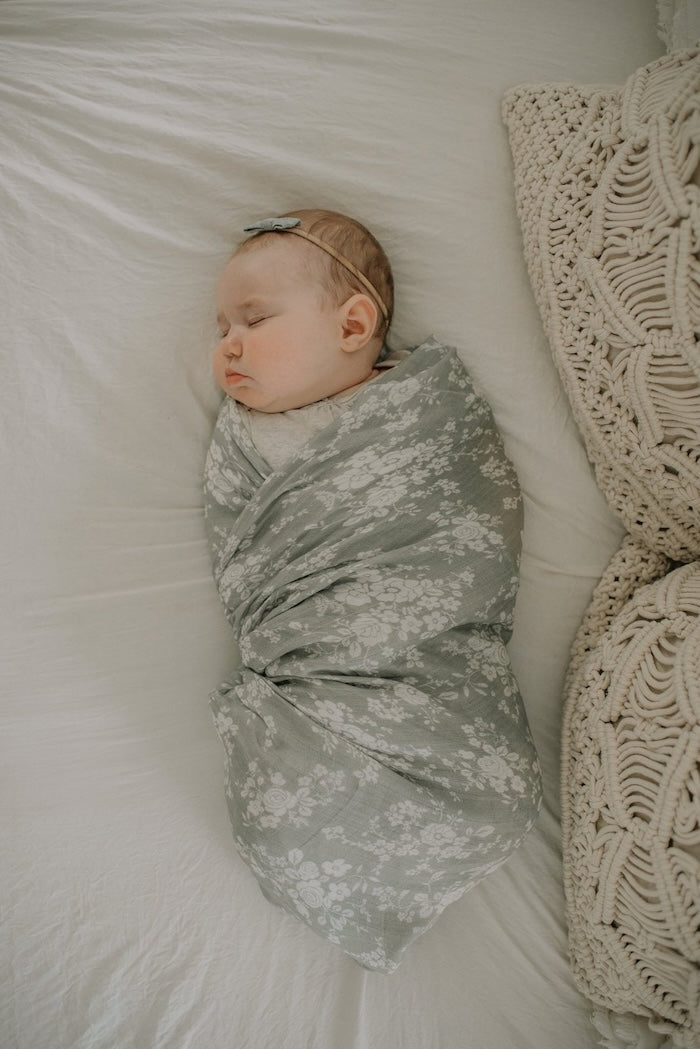 top view photo of a baby girl sleeping soundly and peacefully wrapped in her vintage bouquet swaddle blanket in color Green