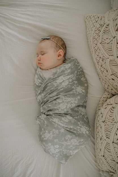 top view photo of a baby girl sleeping soundly and peacefully wrapped in her vintage bouquet swaddle blanket in color Green
