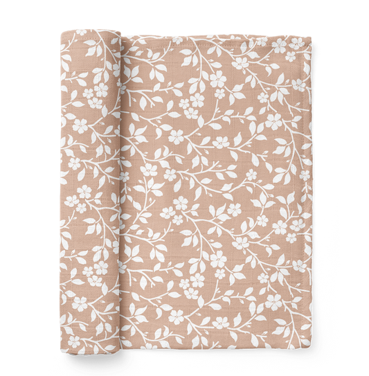 half rolled pink swaddle blanket in the magnolia tree design