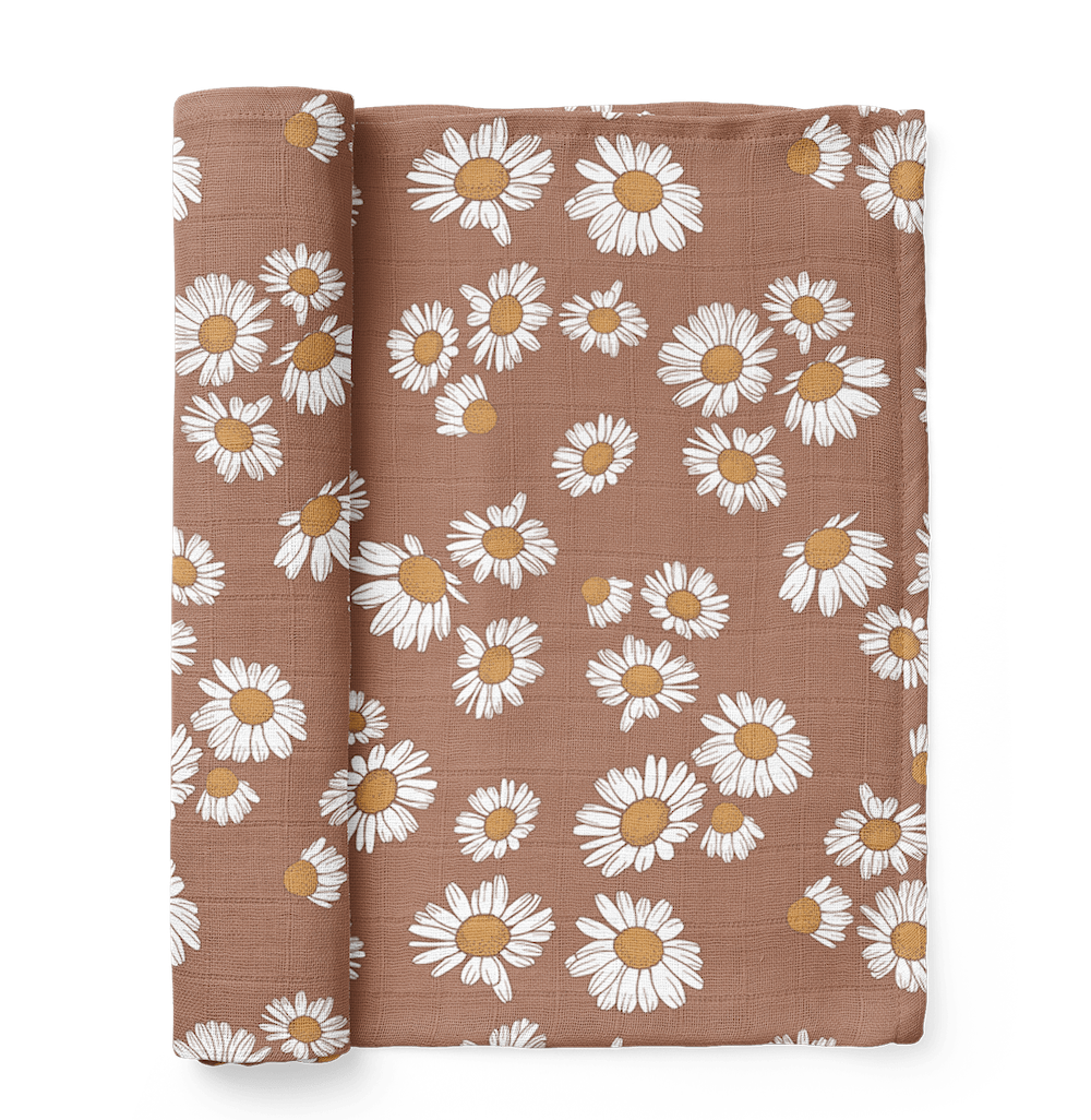 A Mini Wander swaddle half-rolled in earthy clay brown with a Daisy floral design is inspired by nature and characterizes hippie baby names ideal for your little flower child.