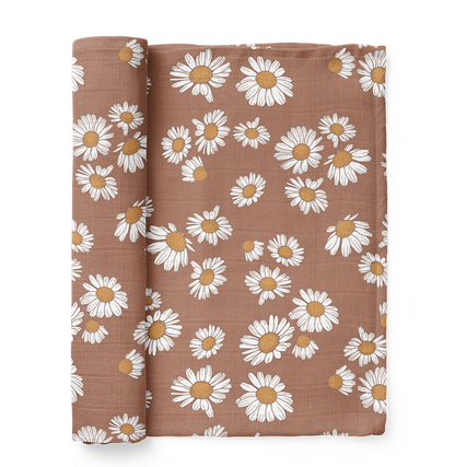A Mini Wander swaddle half-rolled in earthy clay brown with a Daisy floral design is inspired by nature and characterizes hippie baby names ideal for your little flower child.