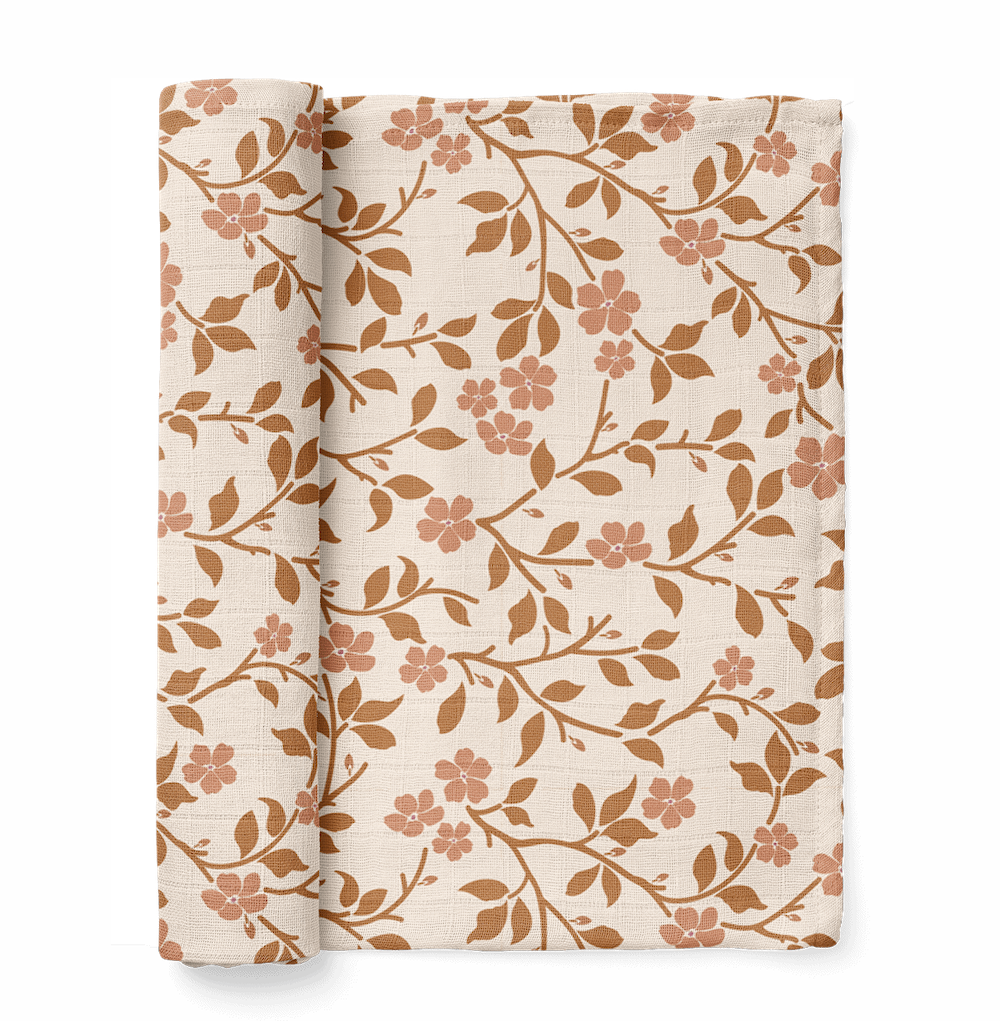 half rolled magnolia tree swaddle blanket in brown color showcasing the rounded petals and leaves of the magnolia tree